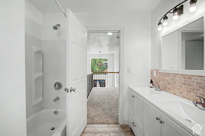 White bathroom vanity with dual integrated sinks, chrome fixtures, and a neutral tile backsplash