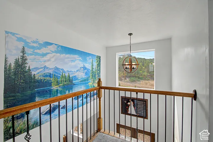 Stairwell featuring wood-finish handrails, black metal balusters, a built-in window, and a contemporary chandelier