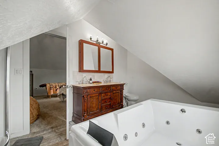White jetted tub with multiple jets, accompanied by a double vanity featuring an ornate wood-finish cabinet, marble-look countertop, and dual mirrors