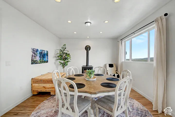 Dining space featuring a black wood-burning stove, recessed lighting, and wood-finish flooring