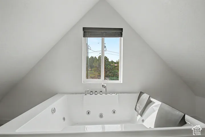 Soaking tub featuring multiple jets, chrome fixtures, and a window with horizontal blinds