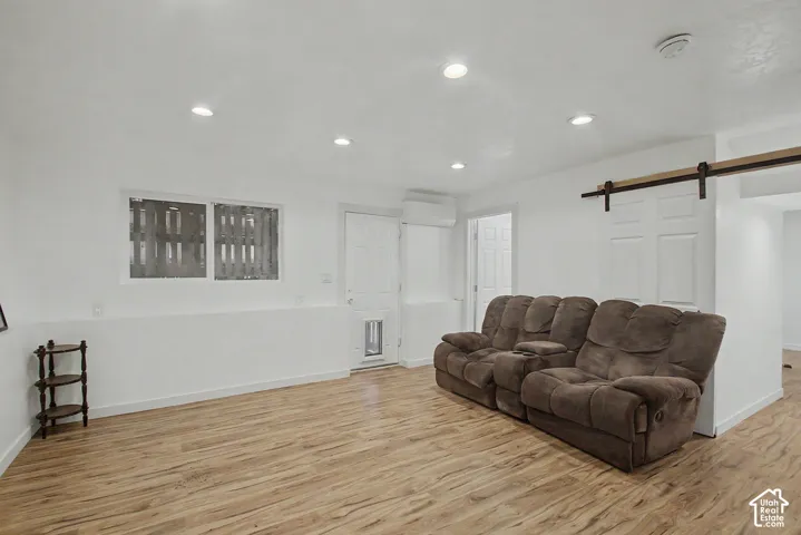 Spacious room featuring wood-finish flooring, recessed lighting, and a barn door entry