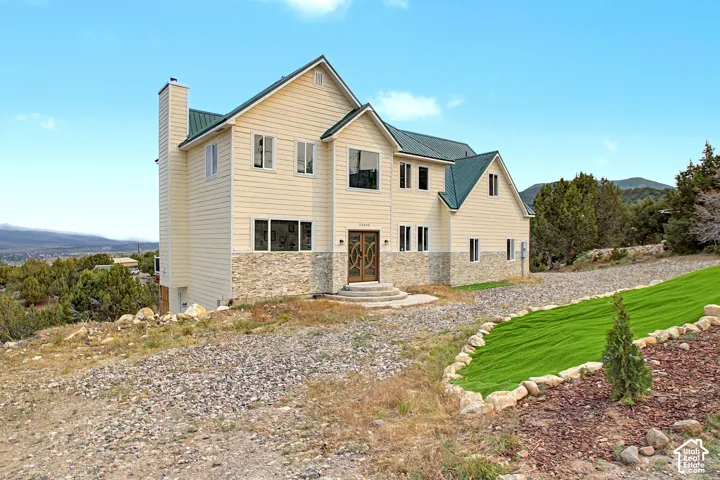 Multi-story residence featuring light-colored siding and a green metal roof