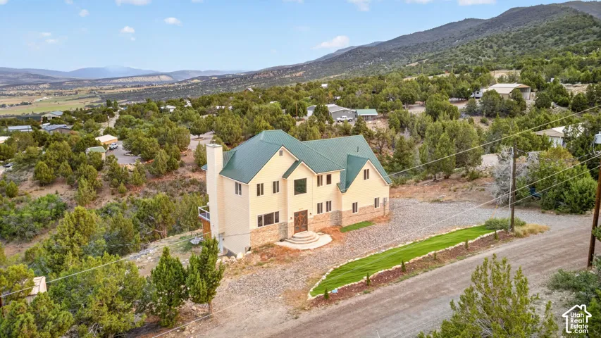 Multi-story residence featuring a green metal roof and a light-colored exterior with stone accents