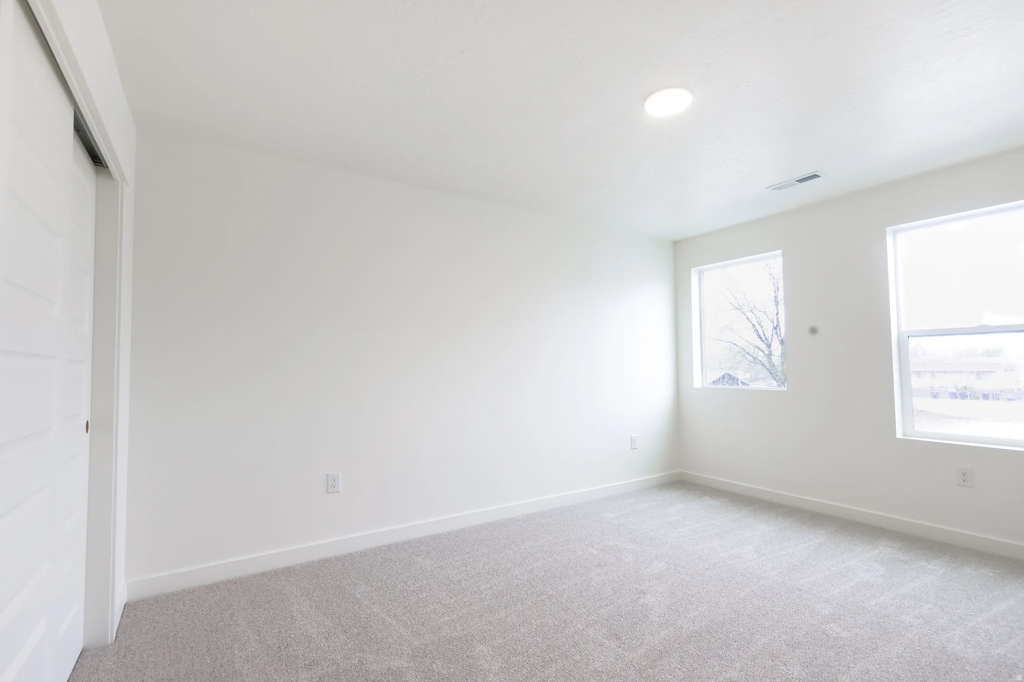 Unfurnished bedroom with light carpet and a closet