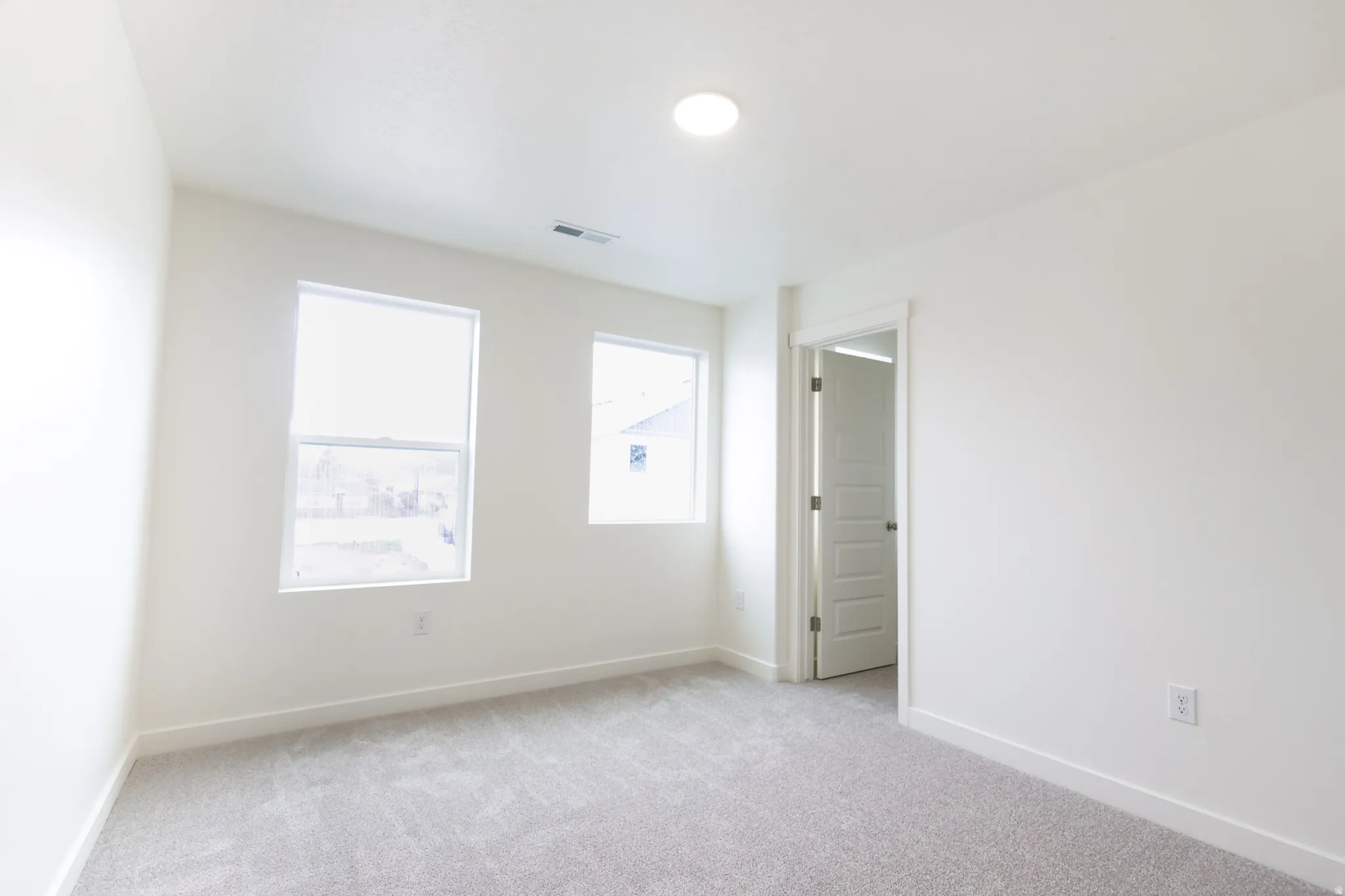 Spare room featuring light carpet and baseboards