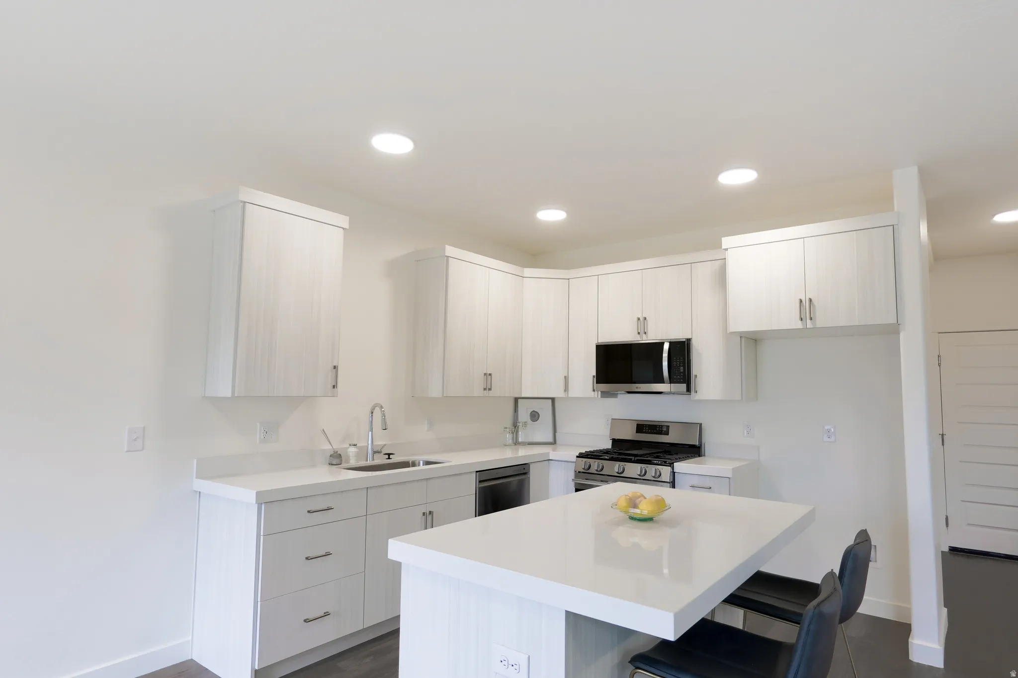 Kitchen with stainless steel appliances, a kitchen breakfast bar, a kitchen island, recessed lighting, and dark wood-style floors