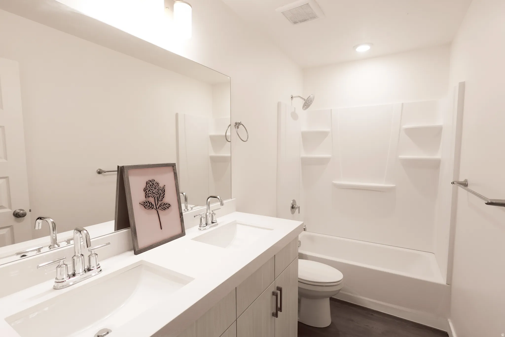 Full bathroom with double vanity, bathtub / shower combination, and dark wood finished floors