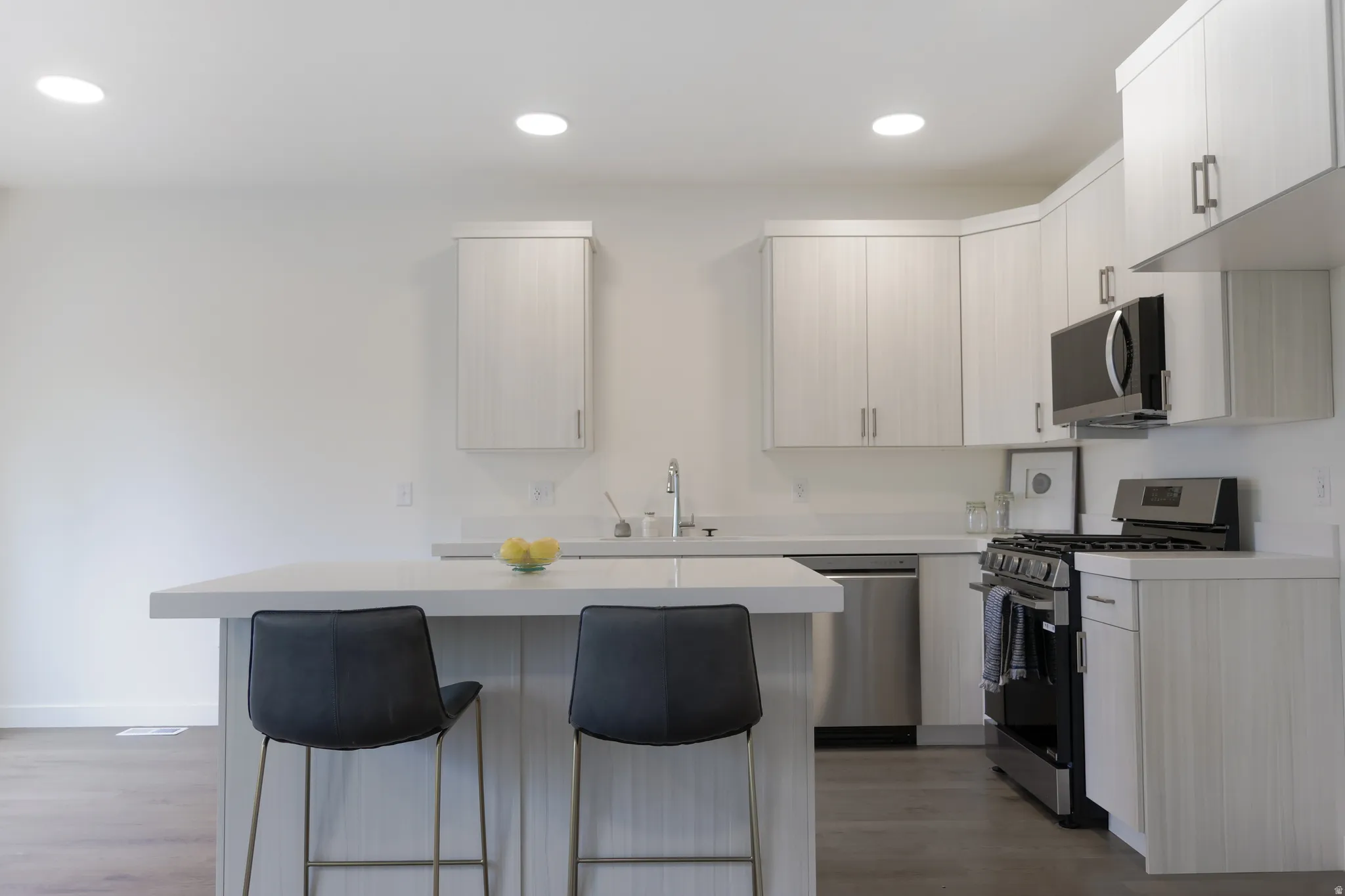 Kitchen featuring stainless steel appliances, a kitchen island, light countertops, a breakfast bar, and light wood finished floors