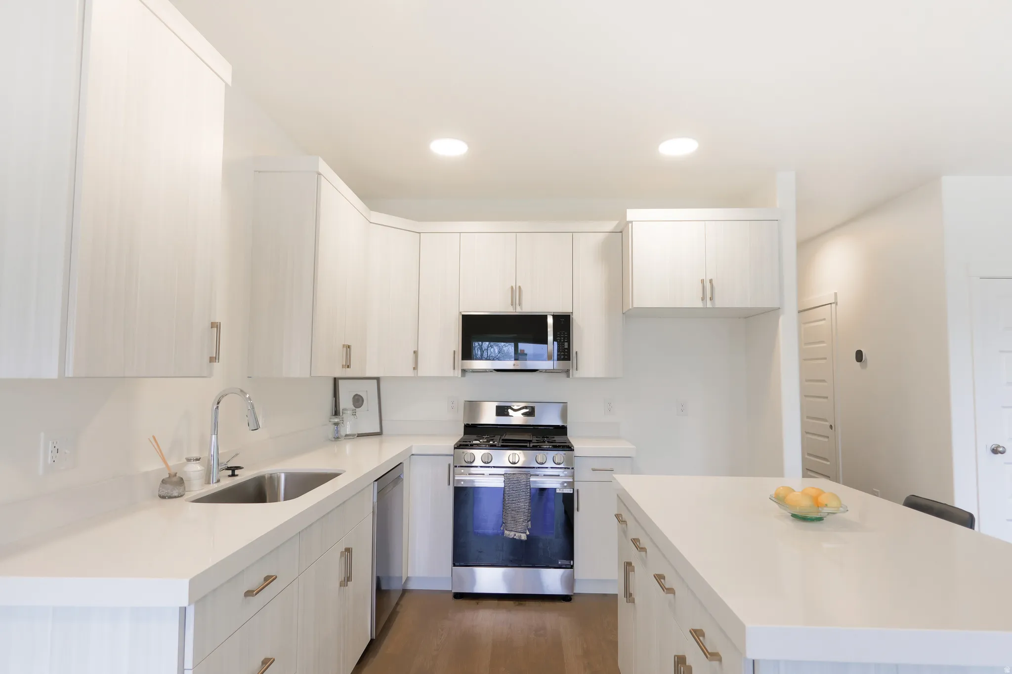 Kitchen featuring stainless steel appliances, a kitchen island, dark wood-type flooring, recessed lighting, and light stone countertops