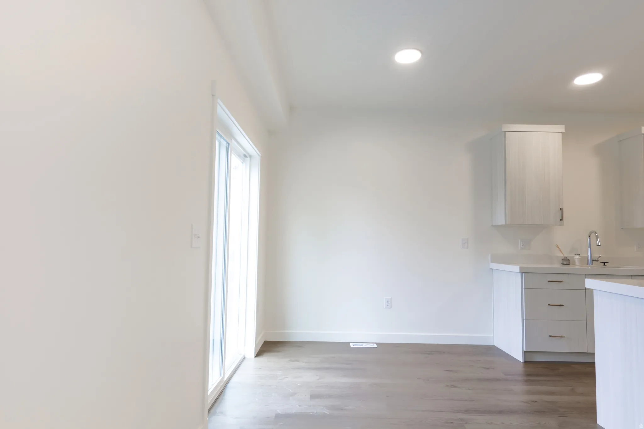 Kitchen with light countertops, light wood-style flooring, recessed lighting, and white cabinets