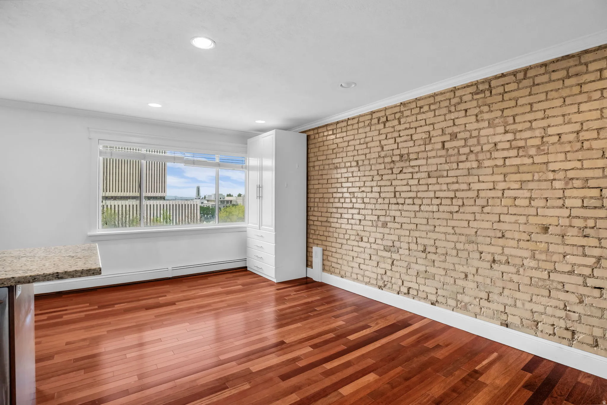 Spare room with brick wall, ornamental molding, wood-type flooring, and recessed lighting