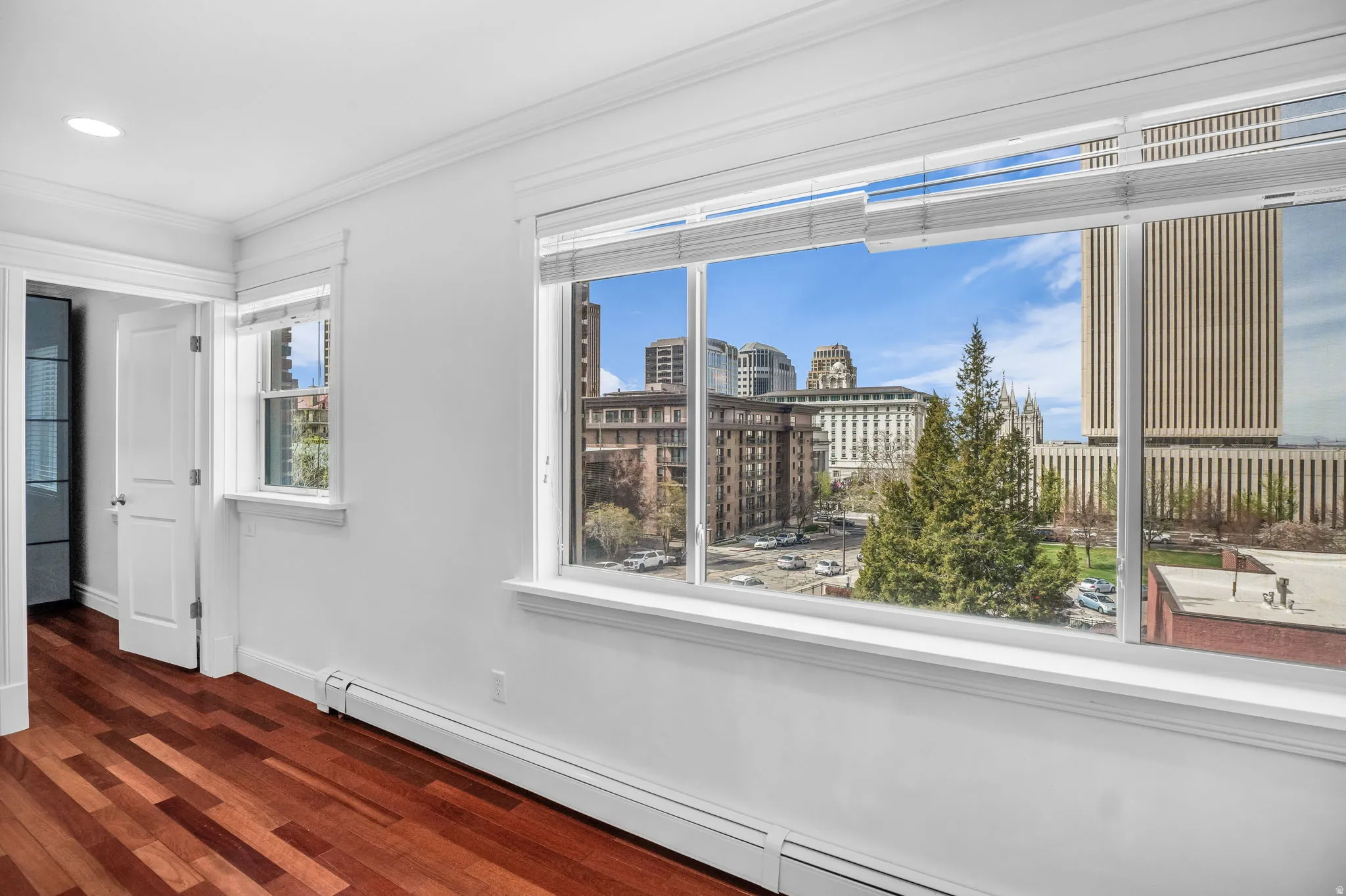 Spare room featuring a baseboard heating unit, crown molding, and dark wood-style floors