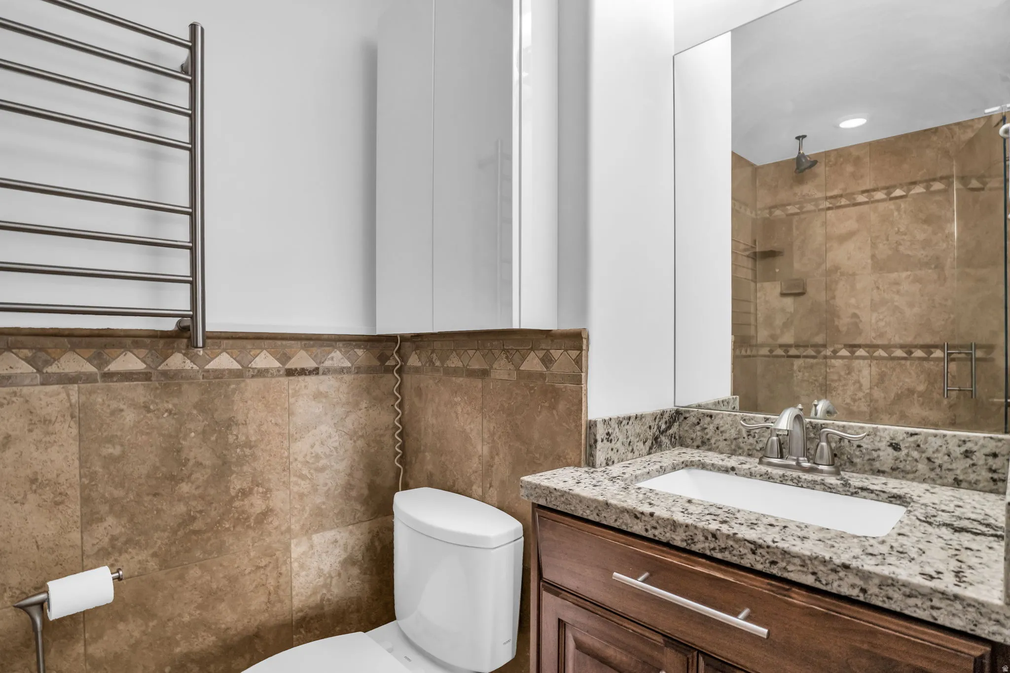 Bathroom featuring a towel warming rack, radiator, vanity, tile walls, and a stall shower