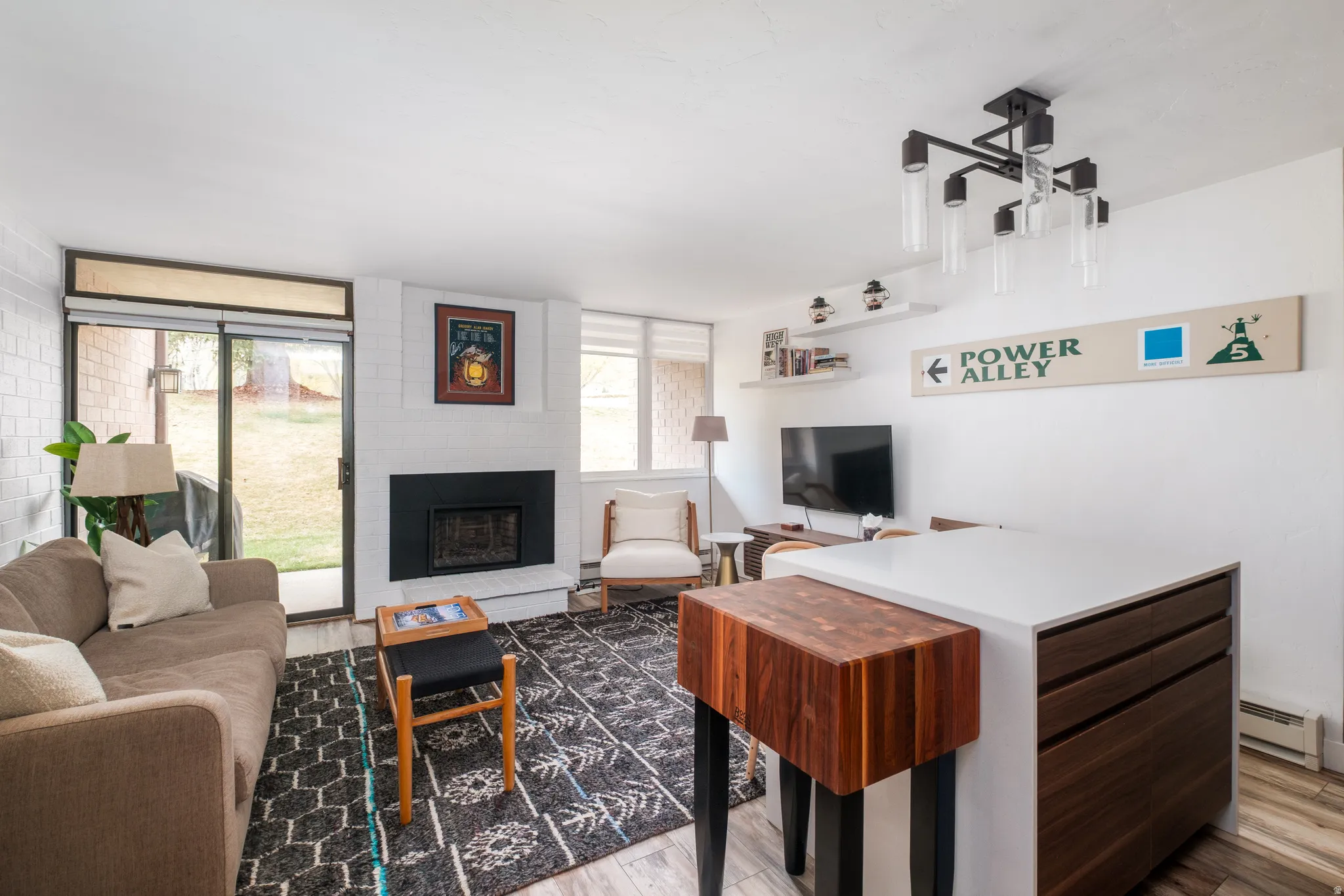 Living area with light wood-style flooring, a baseboard radiator, and a fireplace