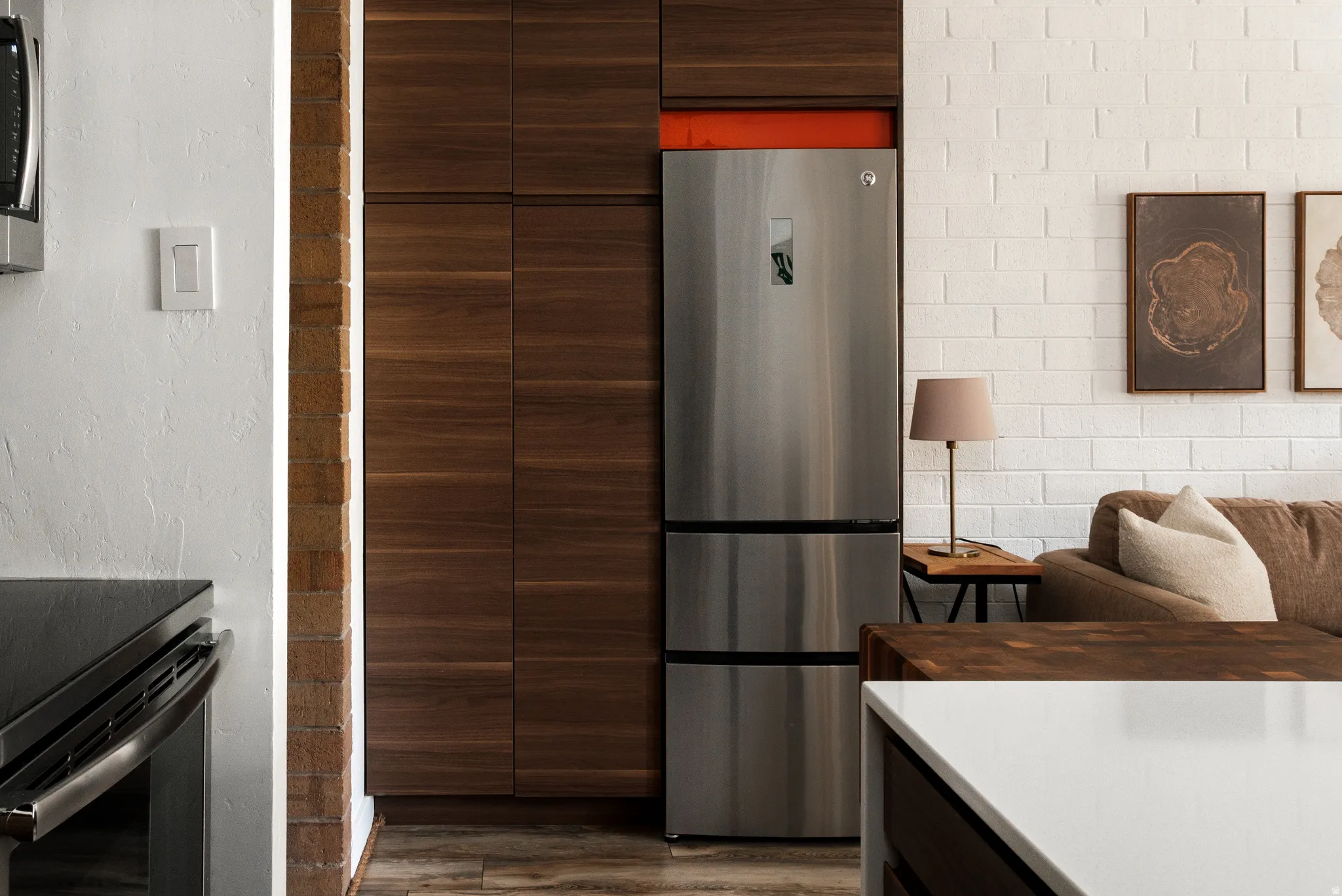 Kitchen featuring dark wood finish cabinets, modern cabinets, freestanding refrigerator, dark wood-type flooring, and black range with electric stovetop
