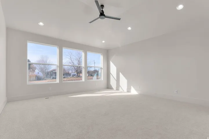 Empty room with light colored carpet, a ceiling fan, and recessed lighting