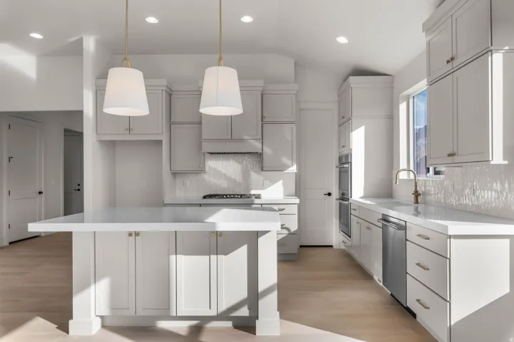 Kitchen with light wood-style floors, vaulted ceiling, a kitchen island, decorative light fixtures, and stainless steel appliances