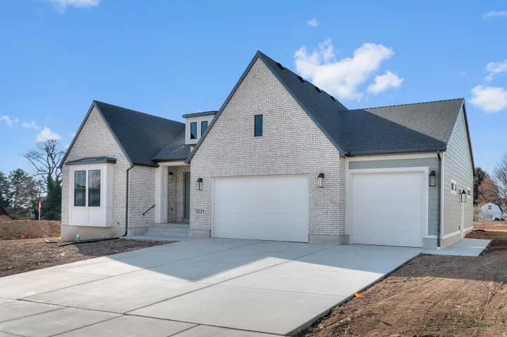 View of front facade featuring driveway, a garage, brick siding, and a shingled roof