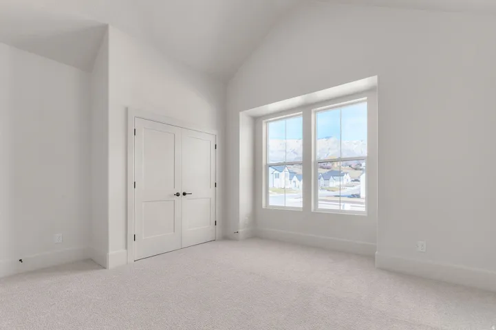 Unfurnished bedroom with carpet floors, vaulted ceiling, and a closet