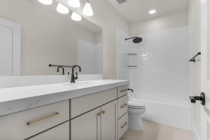 Bathroom with vanity, bathing tub / shower combination, and light tile patterned floors
