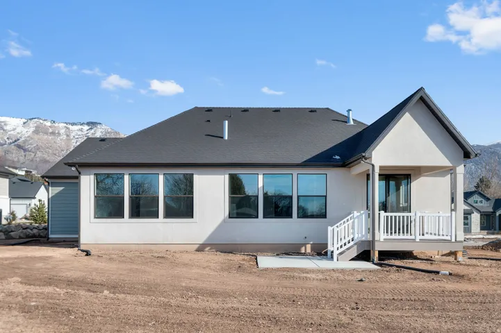 Back of house with a mountain view and roof with shingles
