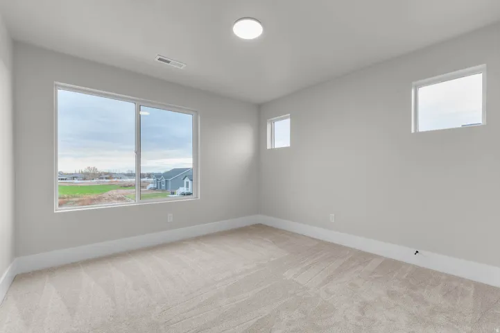Empty room with light colored carpet and baseboards