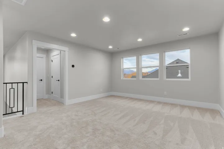 Empty room with light colored carpet and recessed lighting
