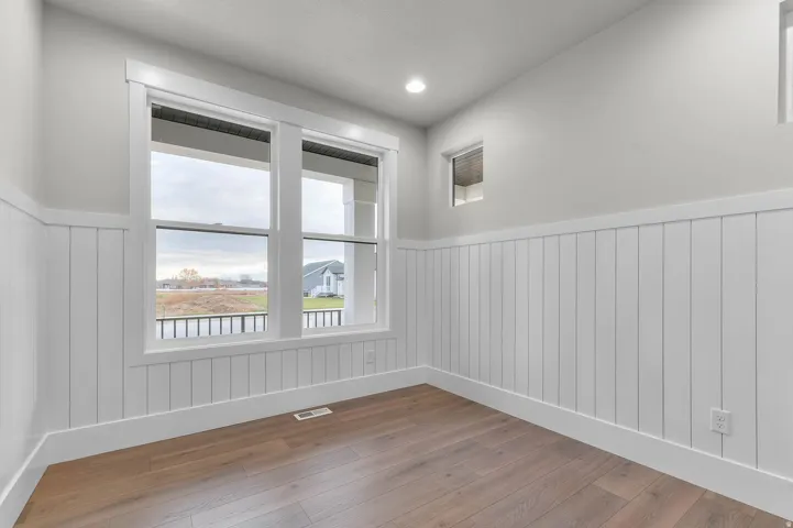 Empty room with wainscoting, wood-type flooring, and recessed lighting