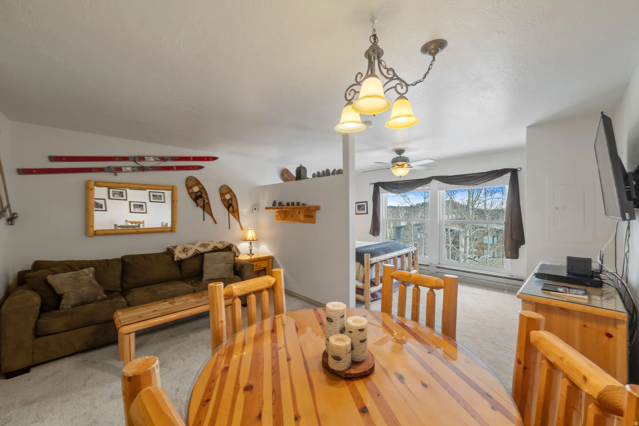 Dining space featuring light carpet, ceiling fan, suspended lighting, and vaulted ceiling