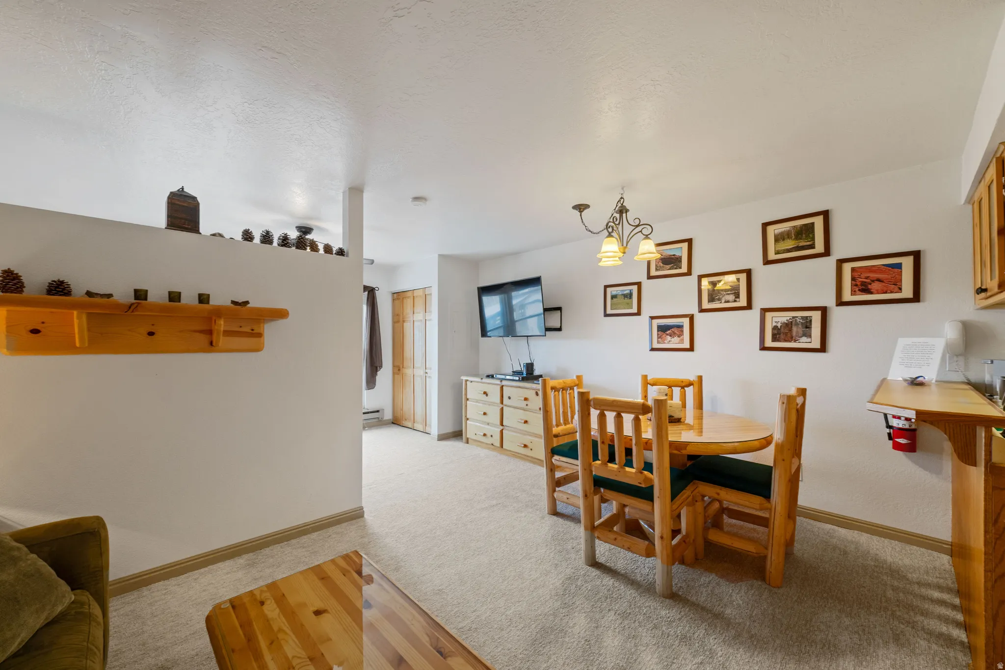 Dining room with suspended lighting, light colored carpet, and a textured ceiling