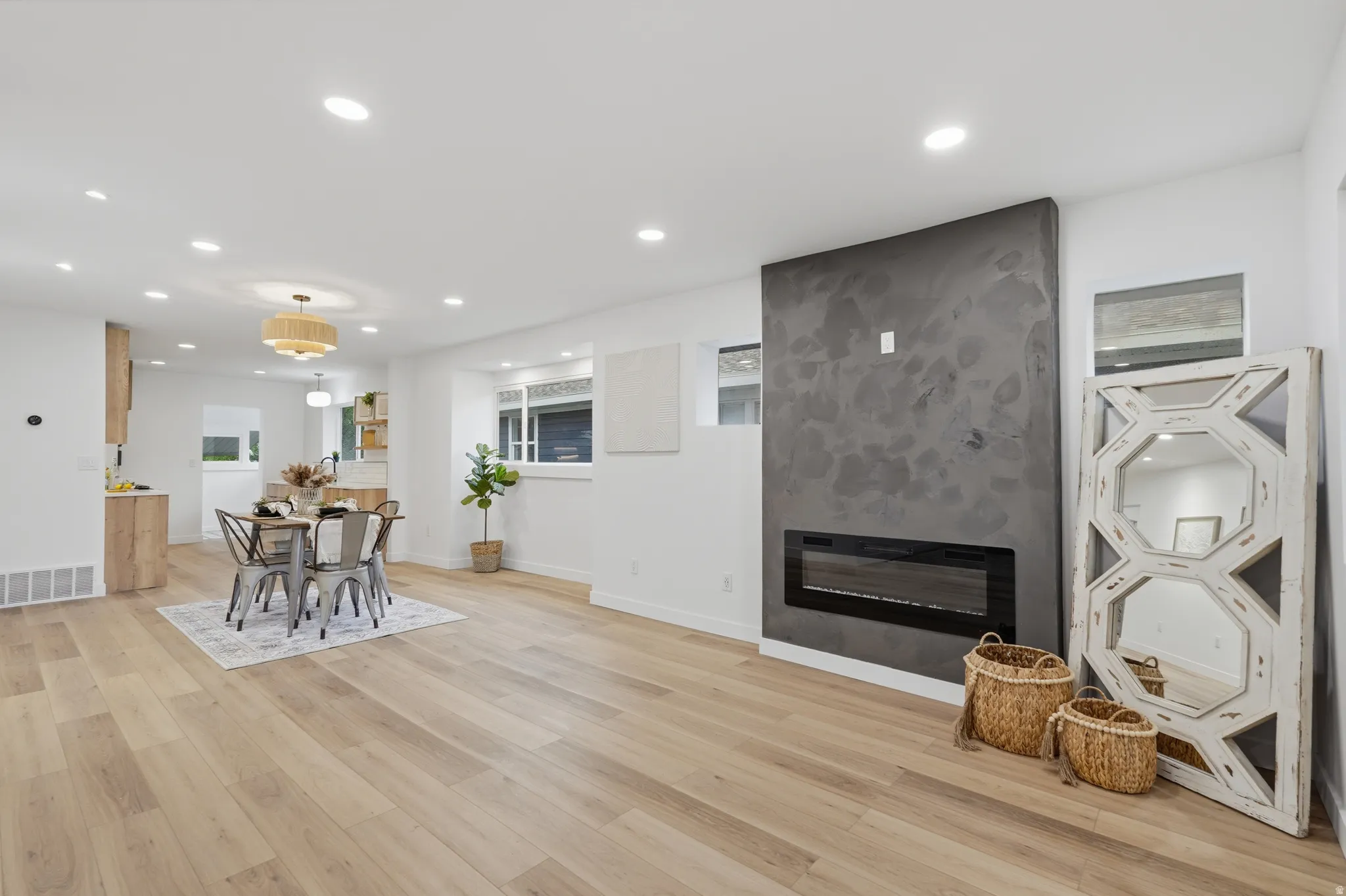 Living room with light wood finished floors, a large fireplace, and recessed lighting