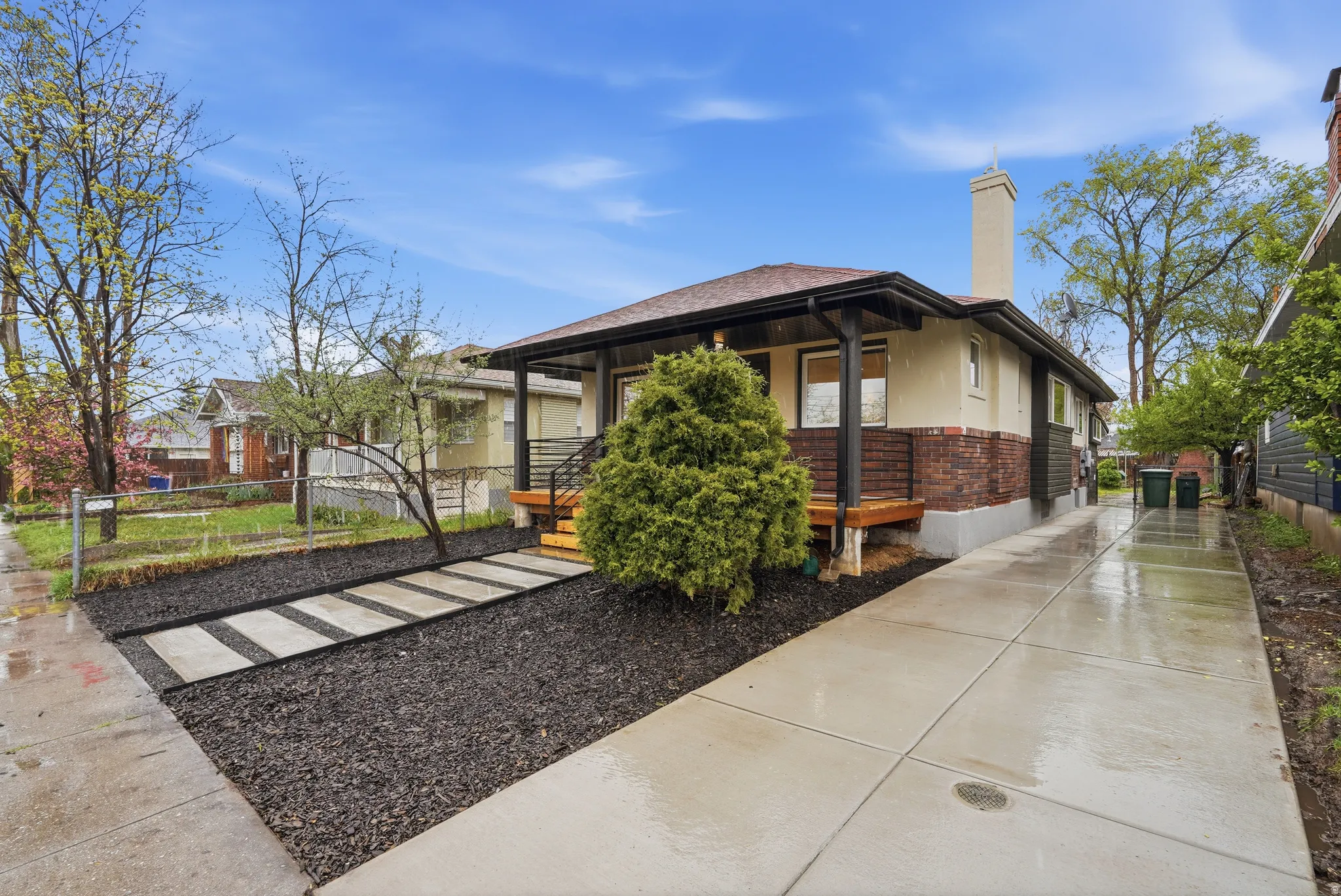 View of side of property featuring a chimney, a porch, brick siding, and stucco siding