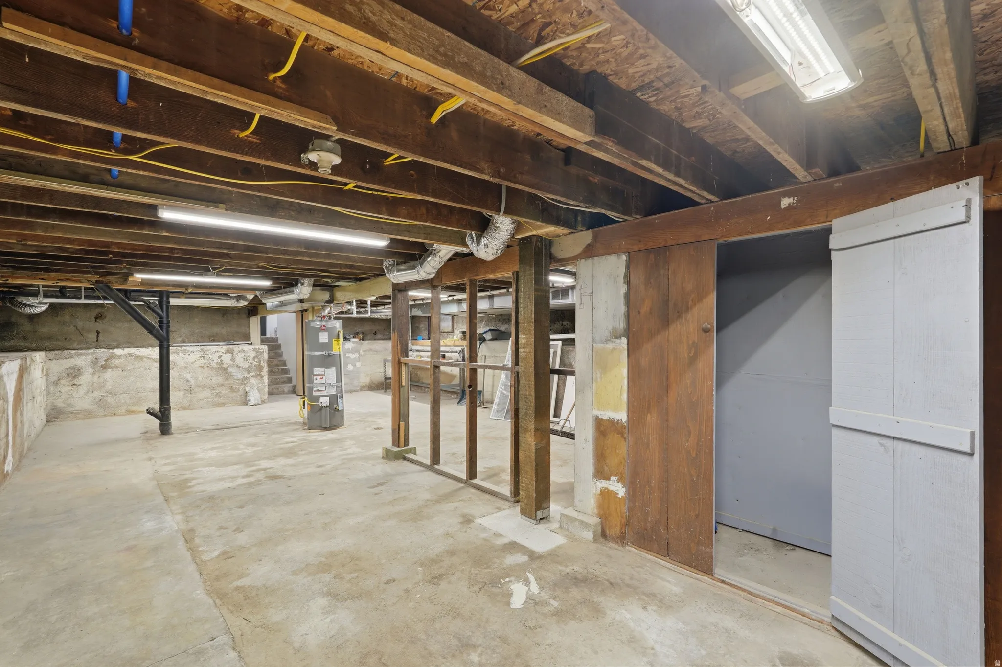 Unfinished below grade area featuring water heater and stairway