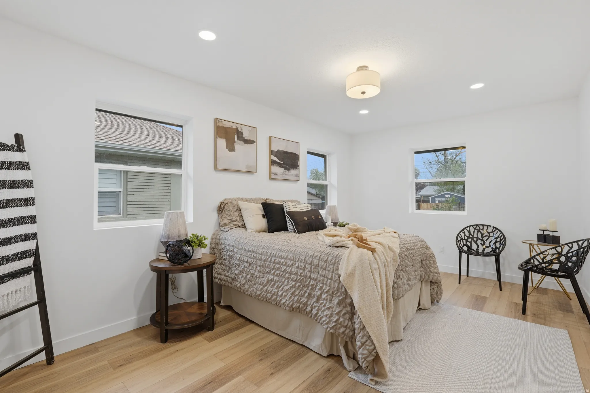 Bedroom with light wood finished floors, multiple windows, and recessed lighting