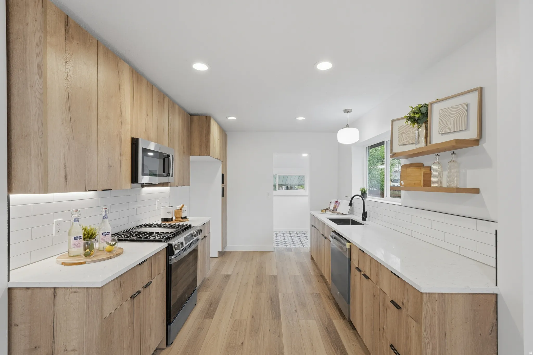 Kitchen with decorative backsplash, stainless steel appliances, light stone countertops, modern cabinets, and light wood-style floors