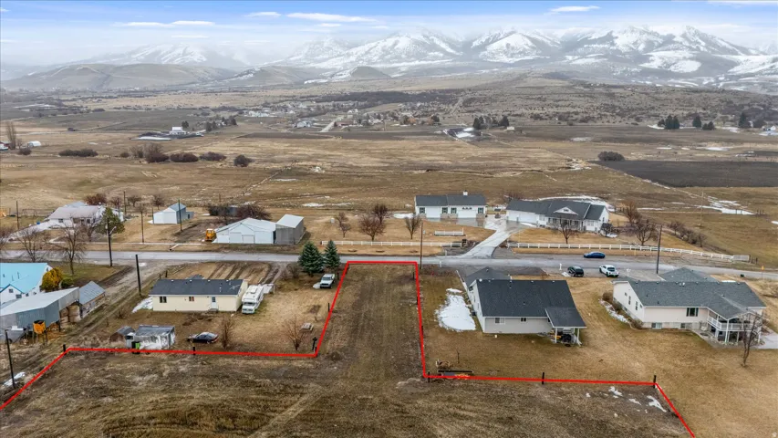 Overview of rural landscape with property parcel outlined, mountains, and nearby suburban area
