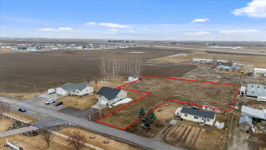 Aerial view of sparsely populated area featuring property parcel outlined and nearby suburban area