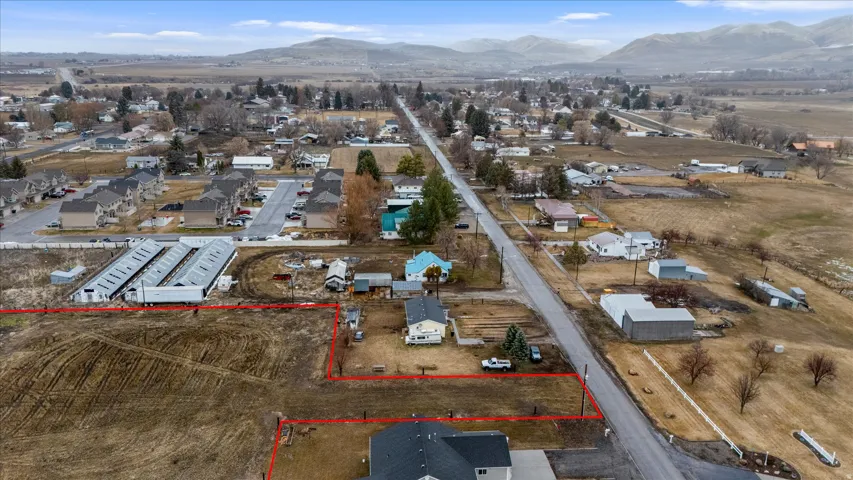 Aerial perspective of suburban area featuring property boundaries highlighted and a mountain backdrop