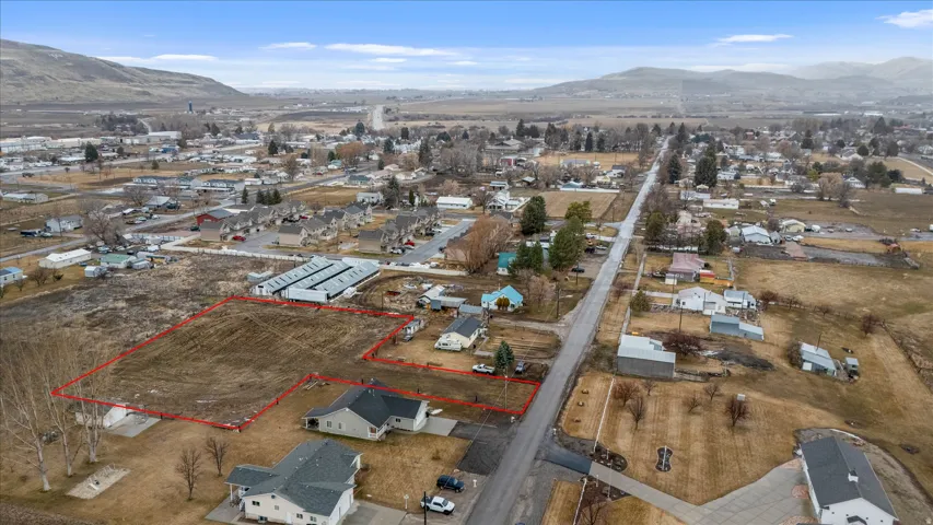 Aerial view of residential area featuring property parcel outlined and a mountain backdrop
