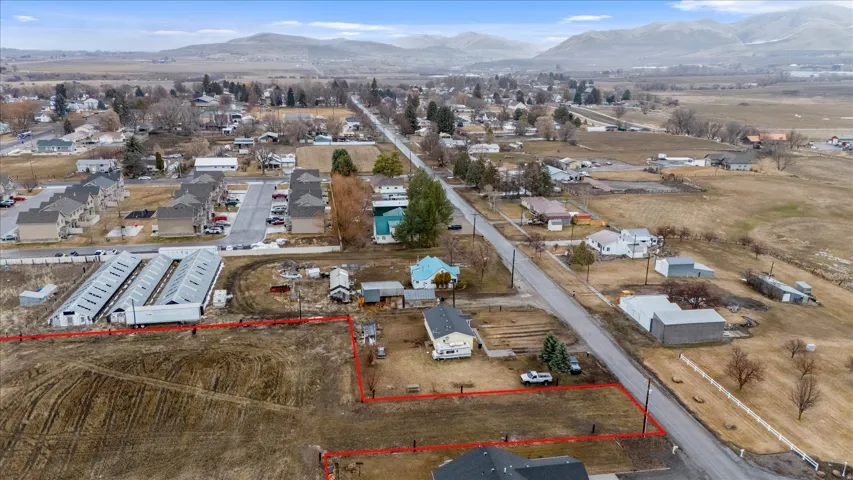 Aerial view of residential area with property parcel outlined and a mountainous background