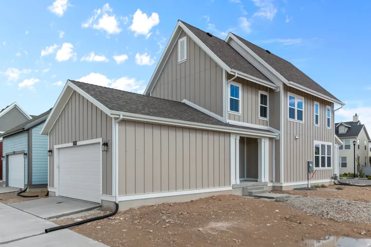View of front of home with board and batten siding, roof with shingles, a garage, and concrete driveway