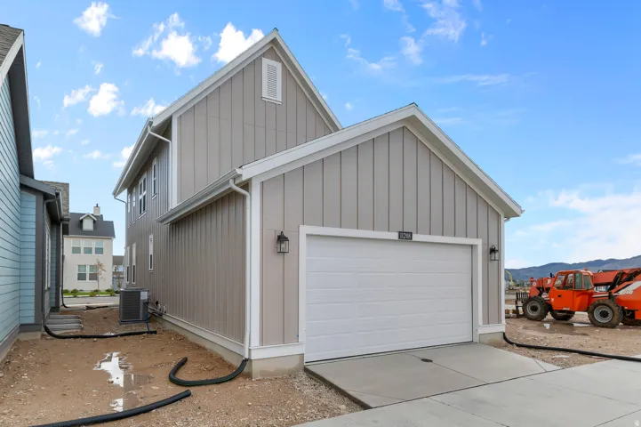 View of home's exterior with board and batten siding, driveway, and a garage