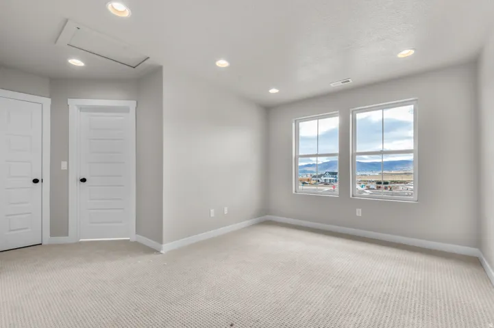 Unfurnished room with a mountain view, recessed lighting, and light carpet