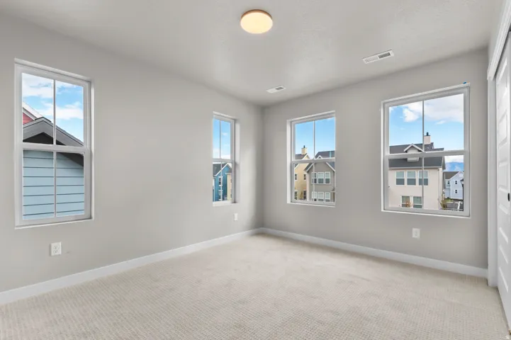 Empty room with light carpet and healthy amount of natural light