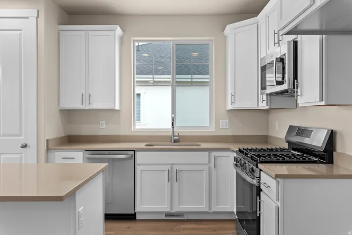Kitchen featuring stainless steel appliances, white cabinetry, and light wood-style flooring