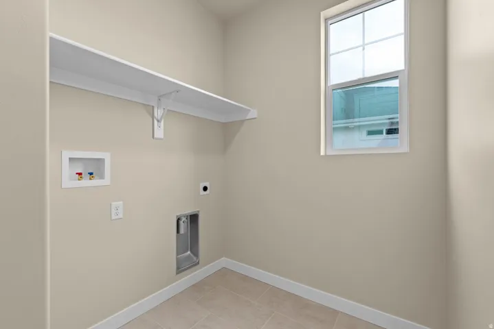 Laundry area with hookup for a washing machine, hookup for an electric dryer, and light tile patterned flooring