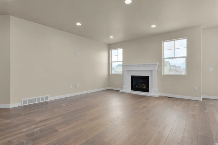 Unfurnished living room featuring recessed lighting, a glass covered fireplace, and dark wood-type flooring