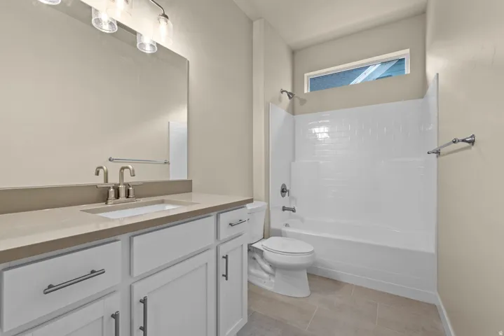Bathroom with vanity, bathtub / shower combination, and light tile patterned floors