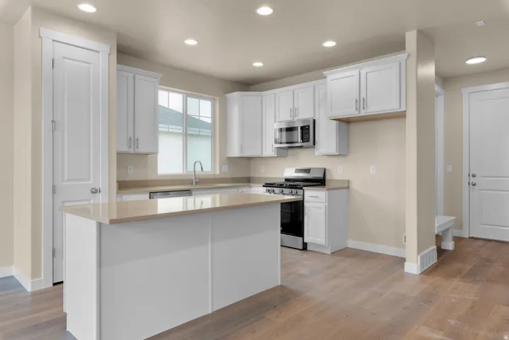 Kitchen with white cabinetry, stainless steel appliances, light wood-type flooring, recessed lighting, and a kitchen island